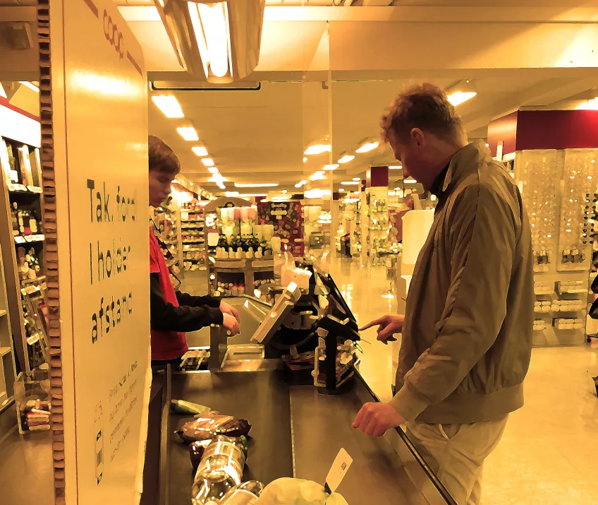 Bearbetat fotografi på en person som betalar vid kassan i en livsmedelsaffär. 